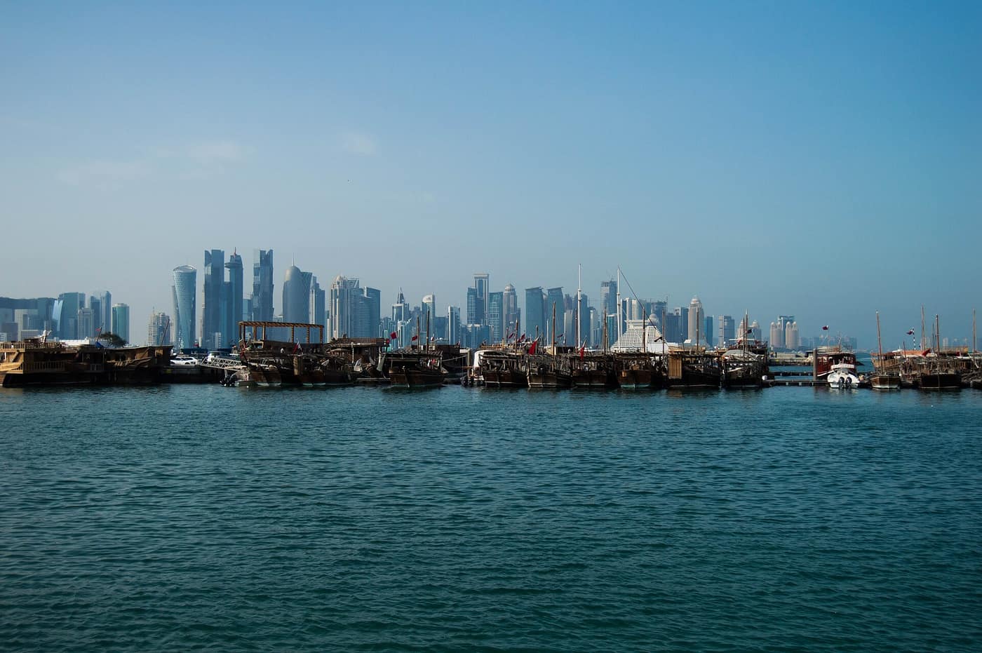 Traditional wooden dhows on the water, with the Doha skyline behind them